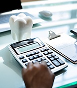 Using calculator and completing form on desk with tooth-shaped paperweight